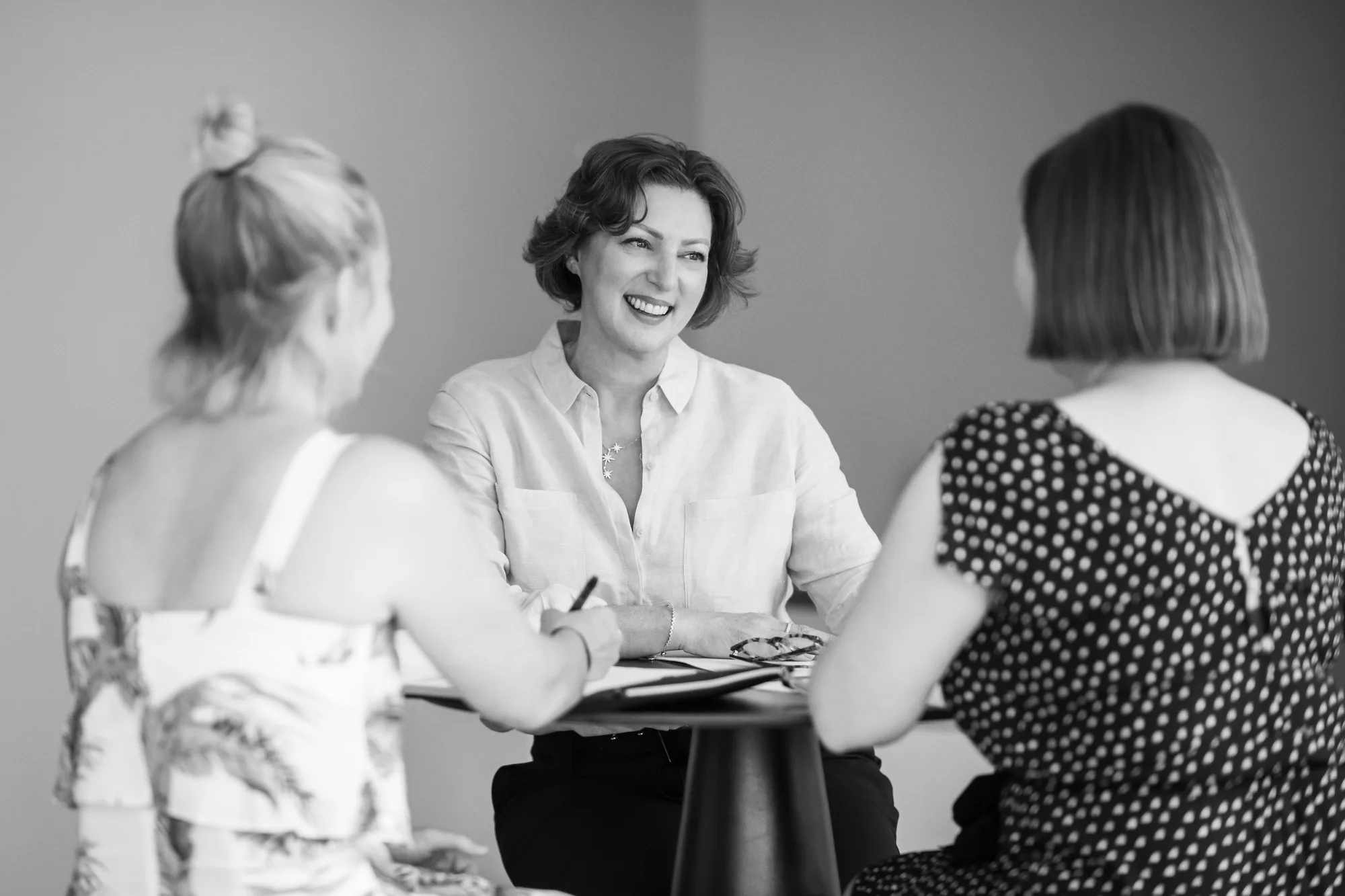 Jacqui Ferris smiling in a coaching conversation with two clients